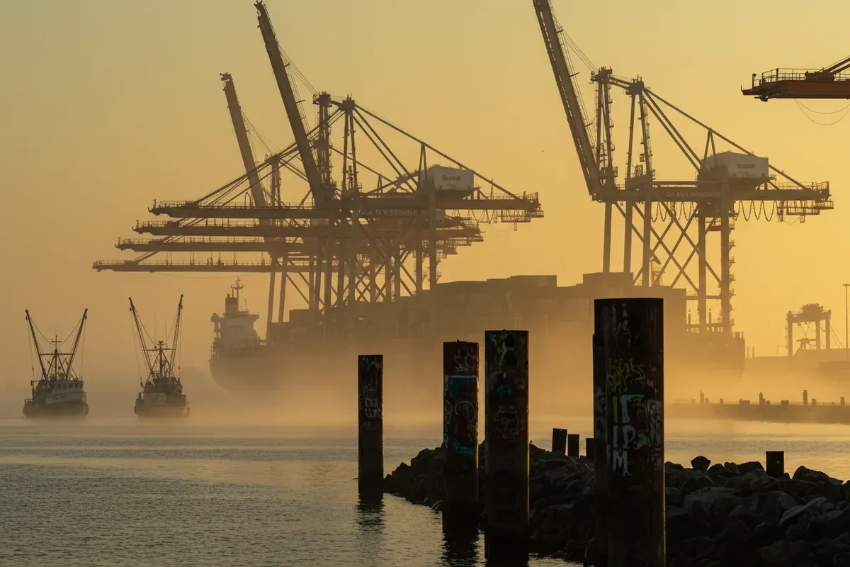 Tall cranes dominate the foggy CaddoBossier Port Commission with several fishing vessels approaching the docks