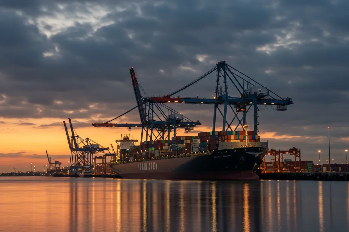 A large cargo ship sits in the Chicot Port Authority harbor reflecting city lights across the water