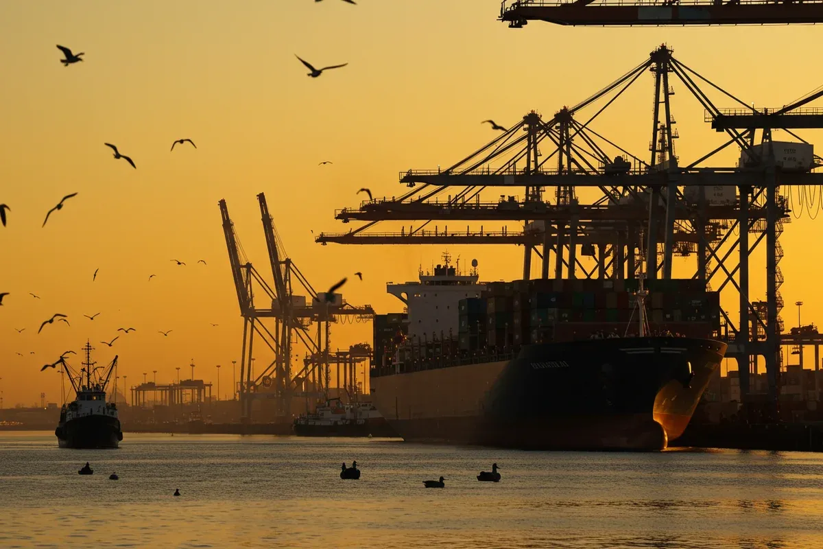 A large cargo ship sits in the foreground of the Port of Columbia with cranes and docks visible in the background