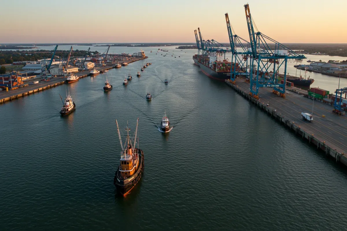 A harbor crane dominates the scene with numerous boats navigating the waterway below