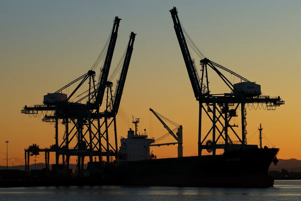 A large cargo ship silhouettes against a dusky sky with towering cranes loading containers at the Port of Walla Walla
