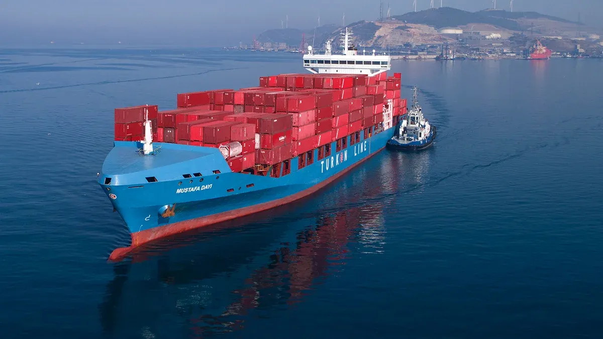 A large container ship the Turkon Line vessel navigates the ocean waters with a predominantly red hull and prominent