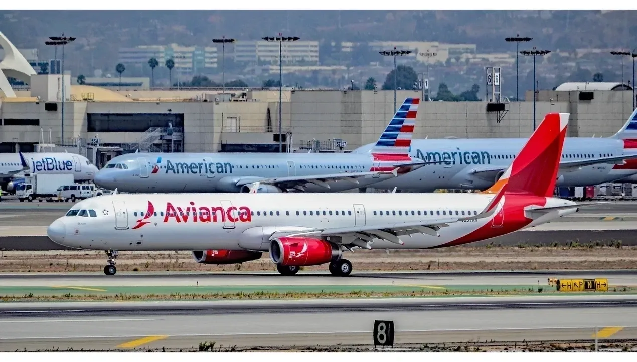 An Avianca airplane stands prominently against a blurred airport background highlighting its vibrant red livery and