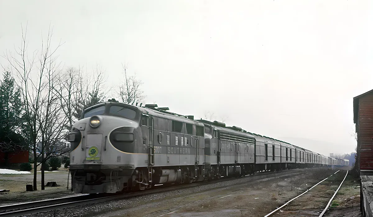 A long silver Birmingham Southern Railroad Company train sits on a track in a snowy landscape The train features multiple
