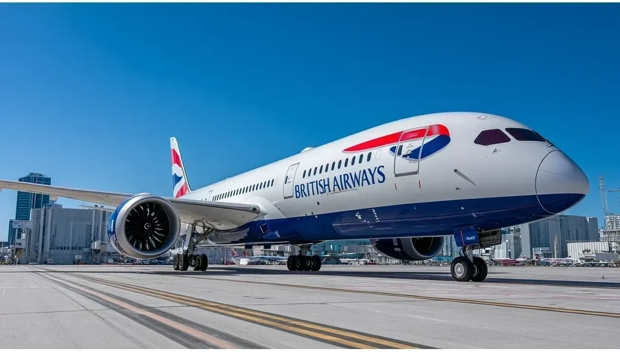 A British Airways aircraft stands on a tarmac with a prominent engine and blue livery The plane waits at the airport gate