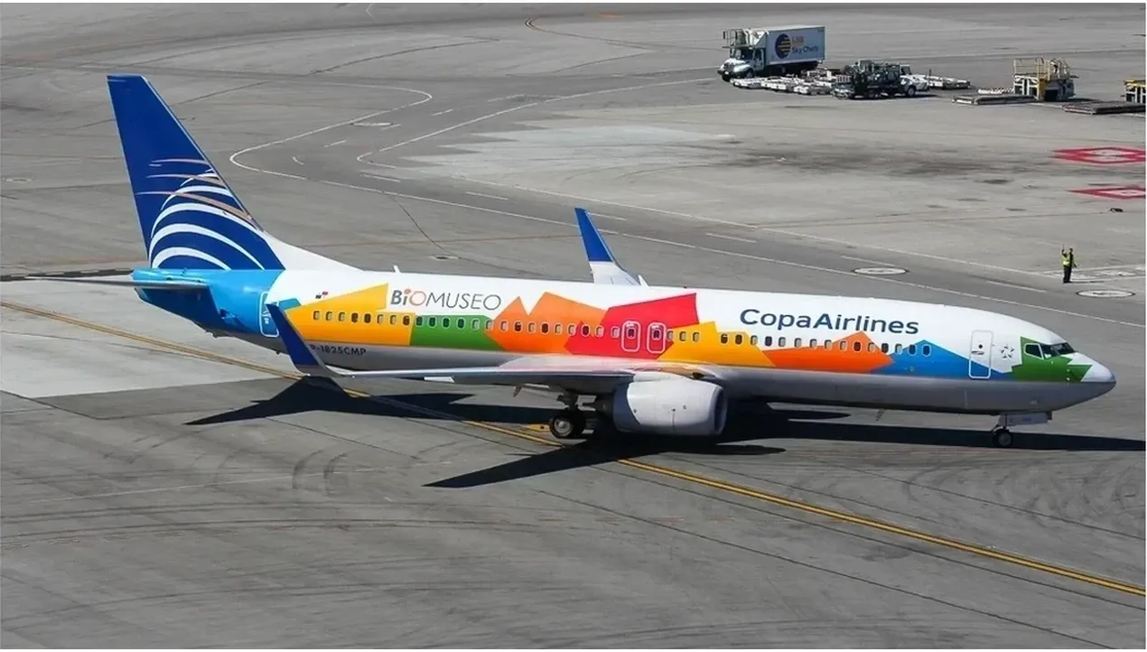 A vibrant Copa Airlines aircraft dominates the image soaring through the sky in brilliant blue and yellow colors a symbol of