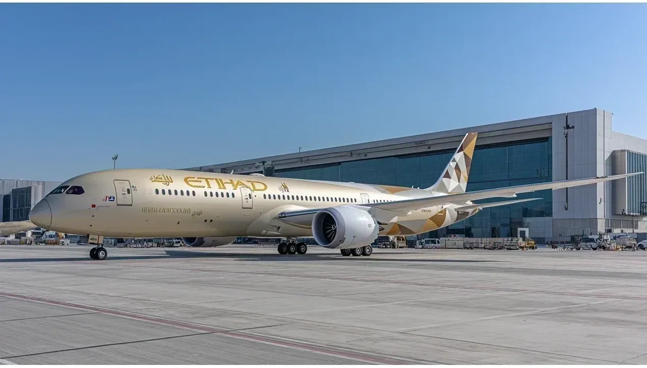An Etihad Airways Airbus A380 aircraft sits on the tarmac at an airport terminal building with ground support equipment