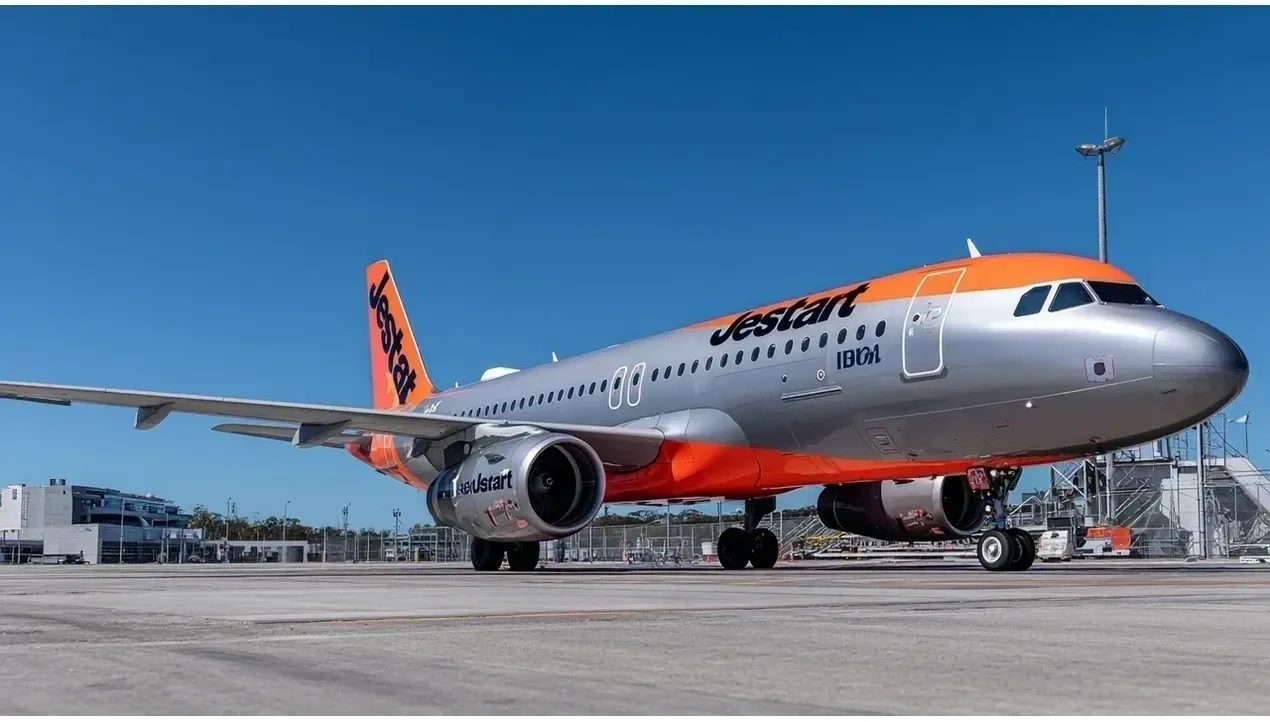 A Jetstar aircraft stands on a tarmac with its blue and white livery prominently displayed ready for flight