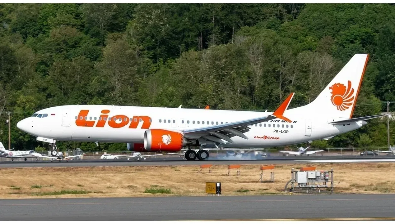 A Boeing 737 aircraft of Lion Air taxis down the runway with its distinctive orange and white tail prominently displayed
