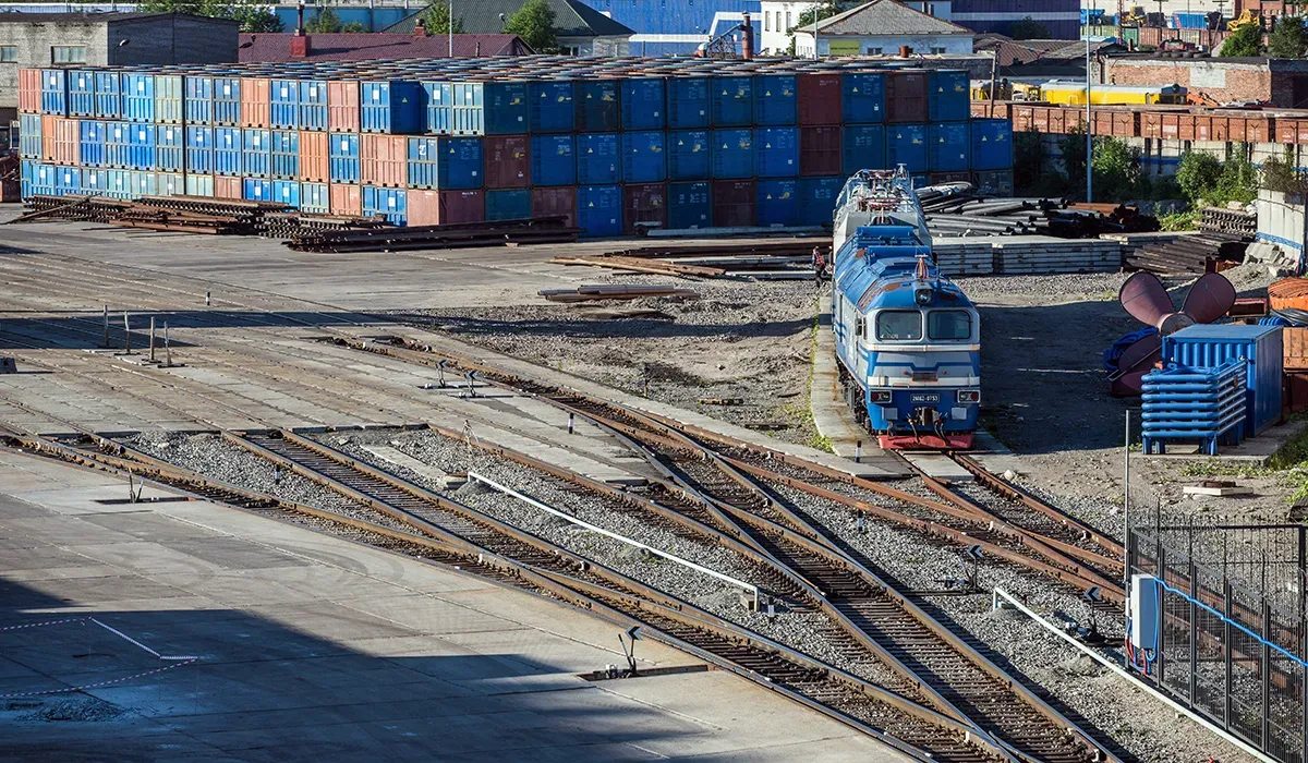 A freight railway yard with multiple tracks and concrete surfaces extends into the distance Trains traverse the yard