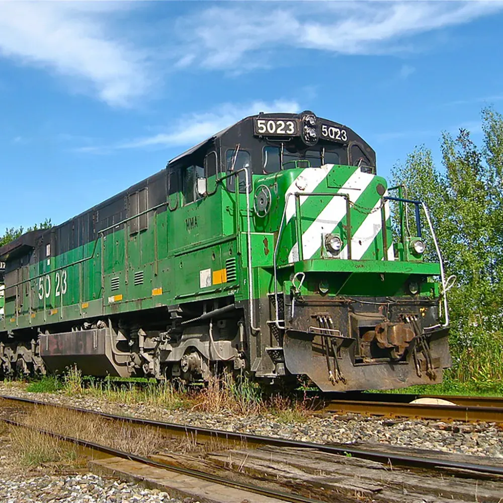 A Montreal Maine and Atlantic Railway freight locomotive stands on a track surrounded by a gravel yard Its cab is painted in
