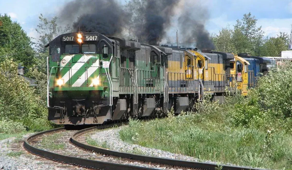 A Montreal Maine and Atlantic Railway freight train moves along a curved track with a silver locomotive leading the way The