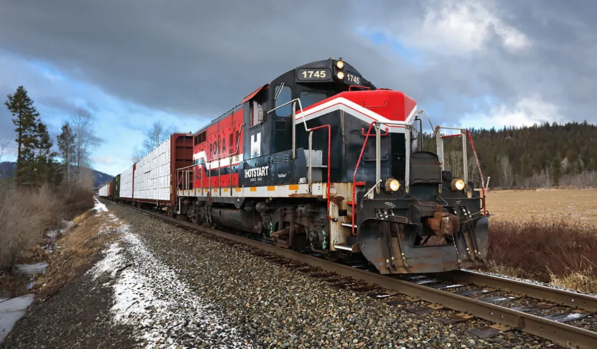 A large red freight train travels along a snowy track with a barren landscape in the background The locomotive is prominent