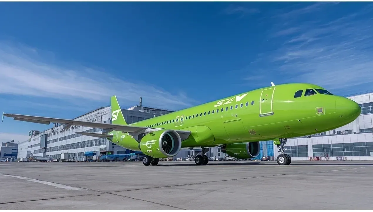 A bright green Airbus A320 aircraft stands on the tarmac at an airport The planes details are clear and its ready for flight