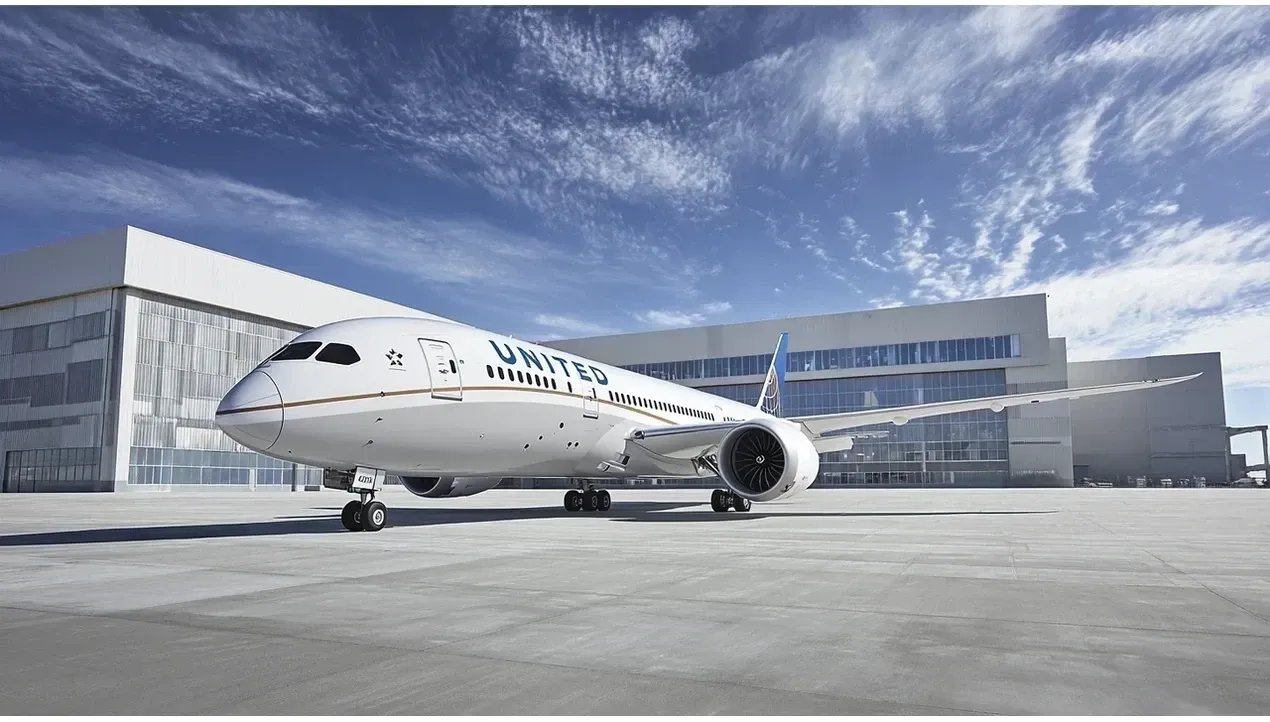 A United Airlines Boeing 737 sits on a concrete pad with a modern building in the background