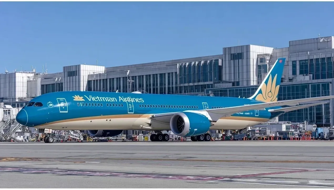 A vibrant Vietnam Airlines aircraft stands at the gate with baggage carts nearby Its distinctive livery creates a striking