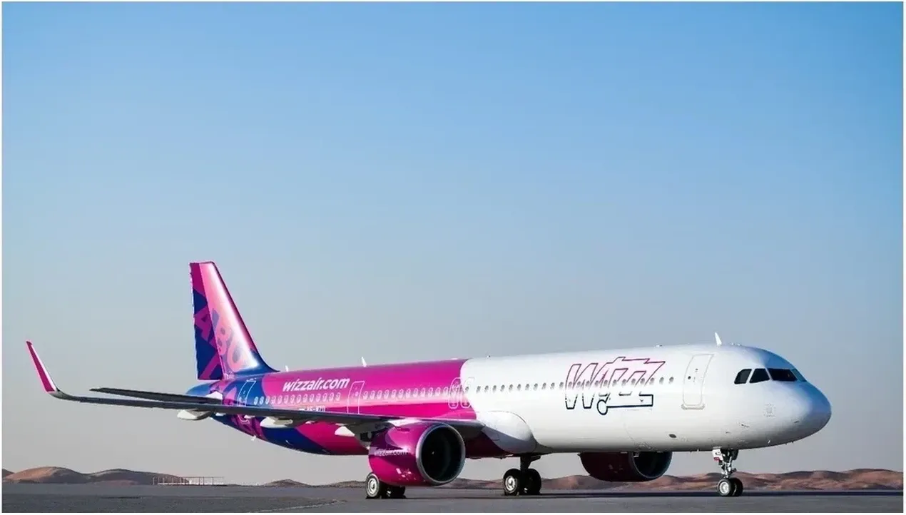 A wizz air Malta aircraft stands on a desert runway under a clear blue sky ready for takeoff its vibrant pink livery