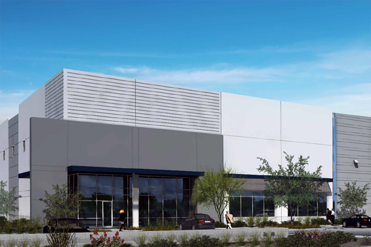 A large gray warehouse building dominates the scene with a blue door and a lightcolored pillar marking the entrance