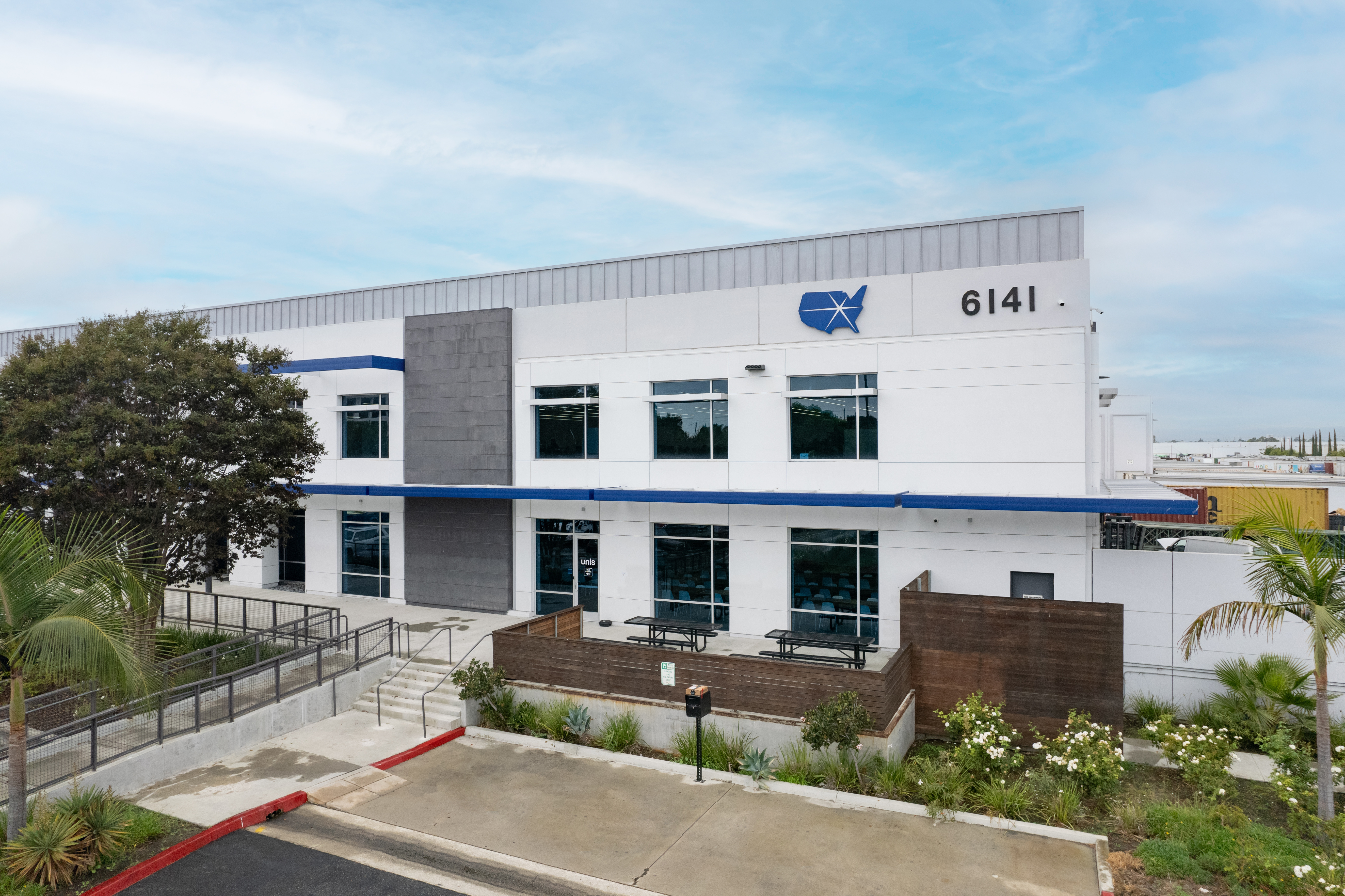 A large modern parking lot with numerous white columns and doors extends into the distance indicating a commercial facility