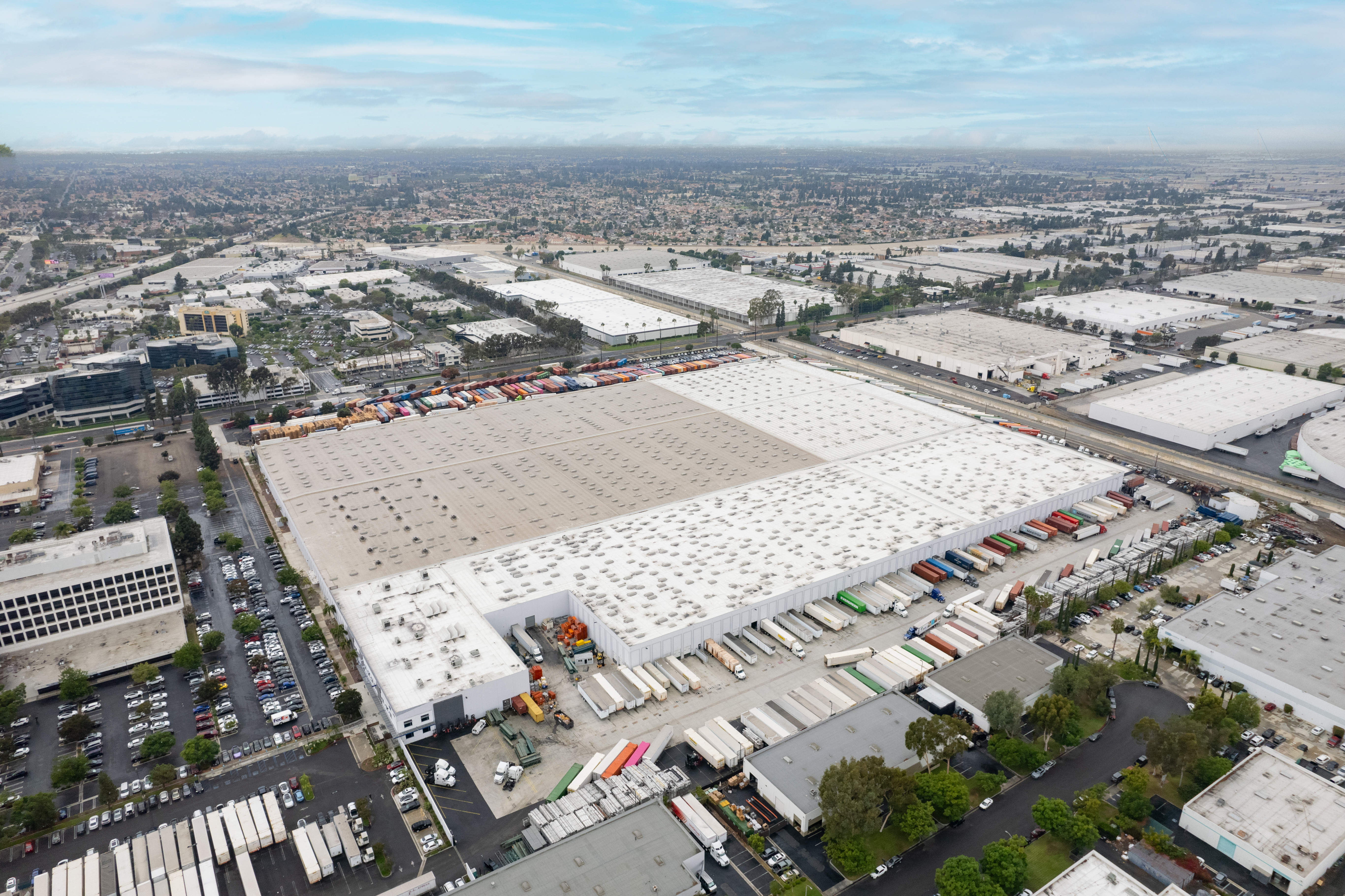 A wide aerial view of a parking lot with numerous brightly colored vehicles lined up neatly showcasing a diverse range of