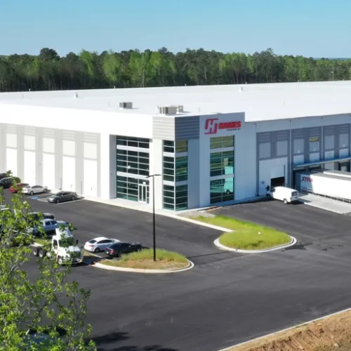 A modern Douglasville Georgia warehouse building with a large paved parking lot and a white truck sits prominently on the