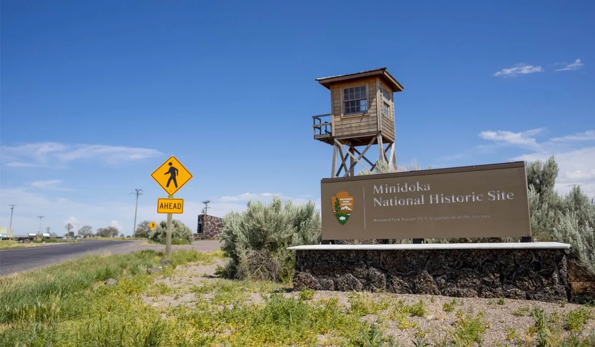 A wooden watchtower stands beside a rural highway in Minidoka Idaho A paved road extends into the distance highlighting the