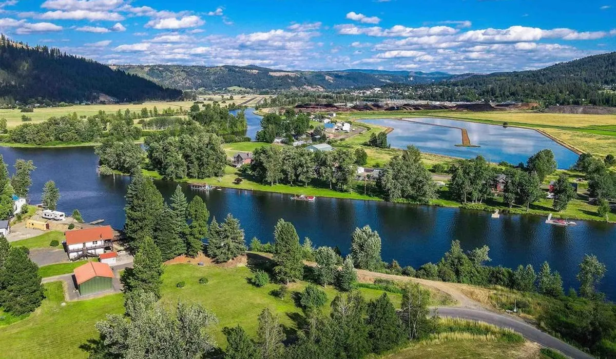 A serene lake reflects houses and trees in St Maries Idaho The image showcases a calm lake with colorful houses lining the